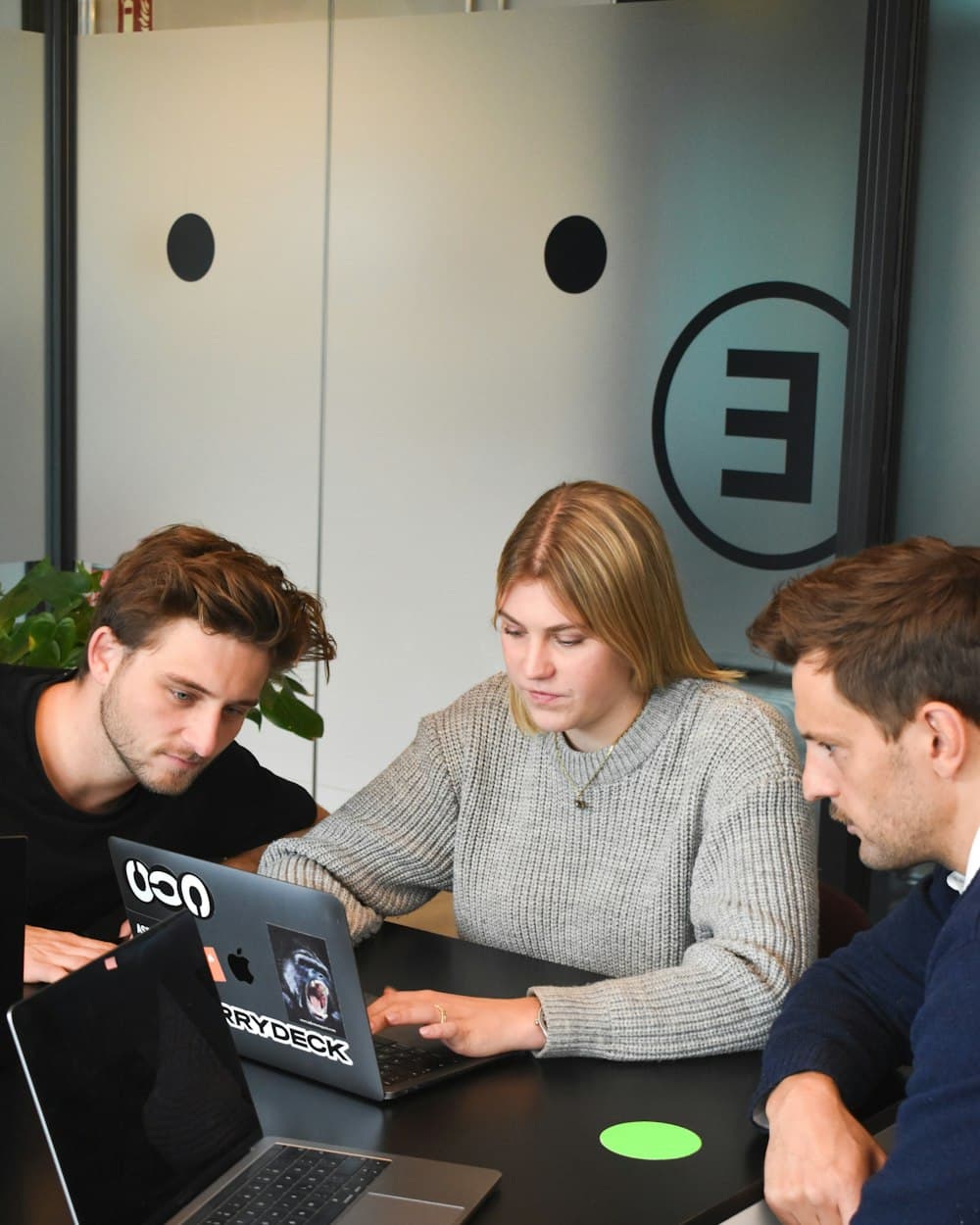 Three colleagues working through a process together on a laptop